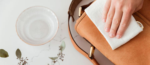 Photo of a hand cleaning a leather handbag