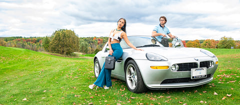 a Couple holding La Coutts Toronto Thermal Handbags in front of a sports car on a golf course