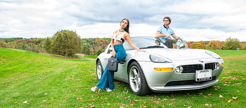 a Couple holding La Coutts Toronto Thermal Handbags in front of a sports car on a golf course 